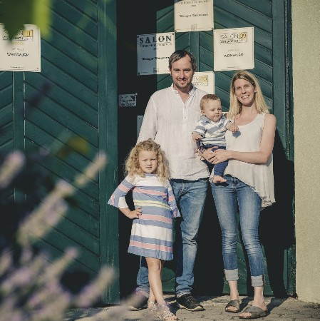 Das Eingangstor mit den Salontafeln der letzten Jahre steht einen Spalt offen. Gut gelaunt stehen Lisa und Georg Weinwurm mit ihren beiden Kindern vor dem Tor. 